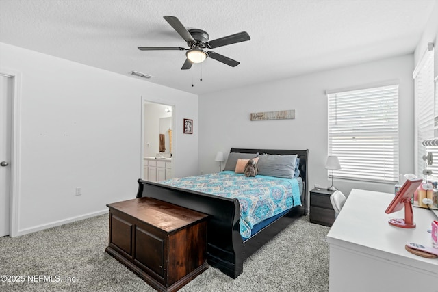 bedroom featuring ceiling fan, light colored carpet, a textured ceiling, and ensuite bathroom