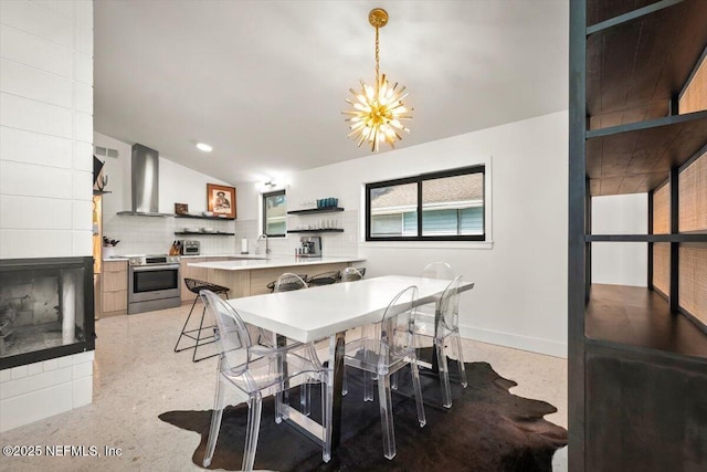 dining room featuring a notable chandelier, vaulted ceiling, and sink