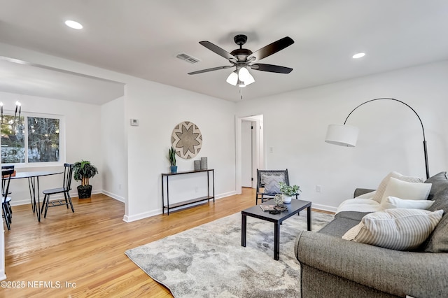 living room with hardwood / wood-style floors and ceiling fan with notable chandelier