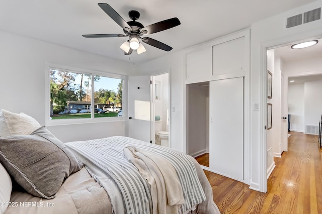 bedroom featuring ceiling fan, ensuite bathroom, a closet, and light wood-type flooring