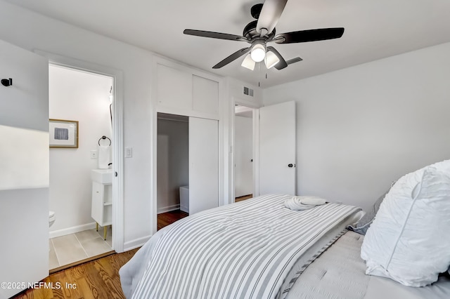 bedroom featuring hardwood / wood-style flooring, a closet, ceiling fan, and ensuite bathroom