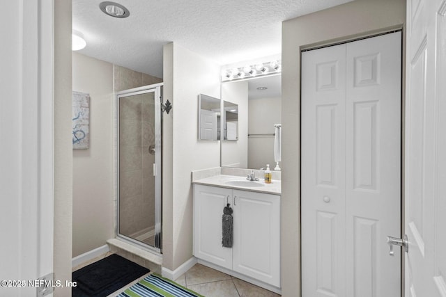 bathroom with vanity, a shower with shower door, tile patterned floors, and a textured ceiling