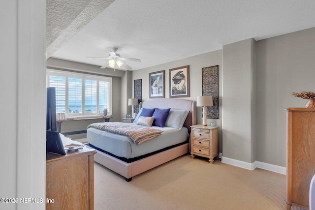 bedroom featuring ceiling fan, light colored carpet, and a textured ceiling