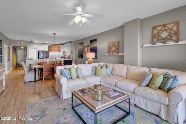 living room featuring ceiling fan and light hardwood / wood-style floors