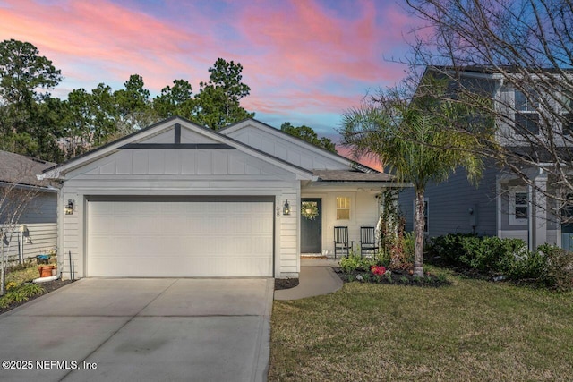 view of front of house featuring a garage, covered porch, and a lawn