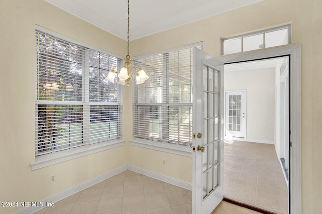 tiled entryway featuring baseboards, ornamental molding, and a notable chandelier