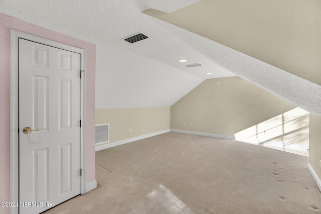 additional living space featuring vaulted ceiling, carpet flooring, visible vents, and baseboards