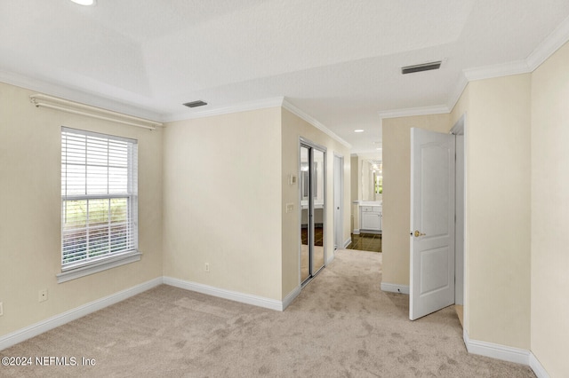 unfurnished room with light colored carpet, visible vents, crown molding, and baseboards