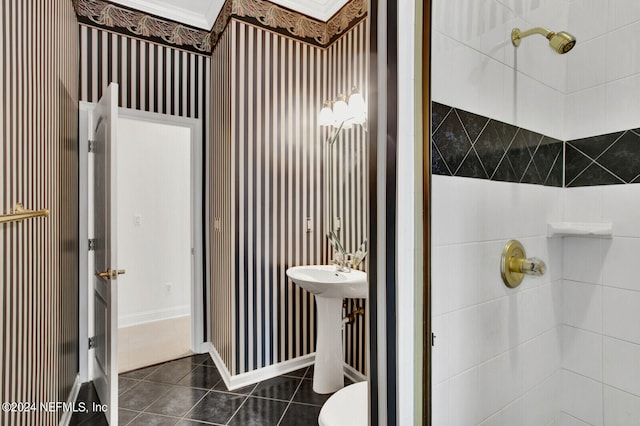 bathroom featuring toilet, baseboards, a tile shower, and tile patterned floors