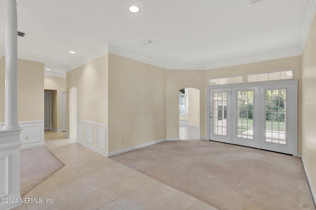 spare room featuring light carpet, a healthy amount of sunlight, decorative columns, and arched walkways