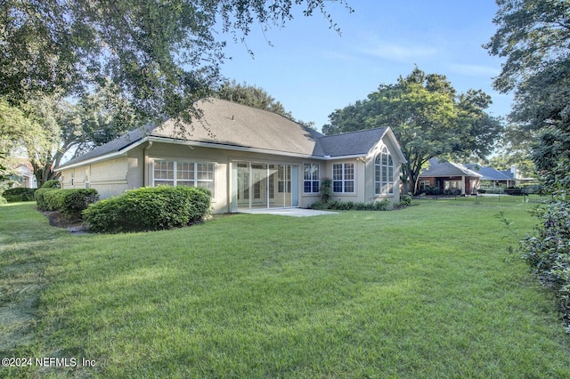 back of property with a lawn and stucco siding