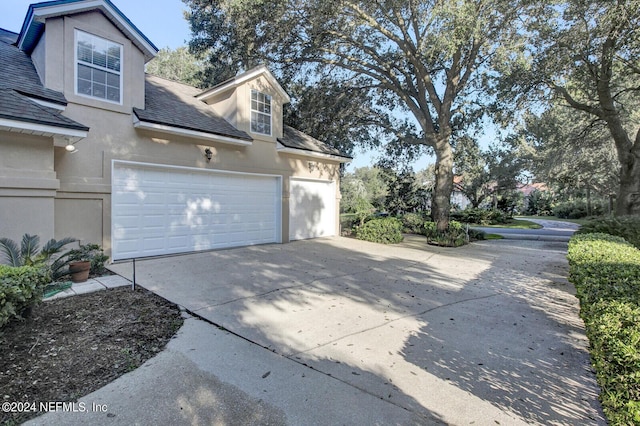 view of property exterior featuring a garage, roof with shingles, driveway, and stucco siding