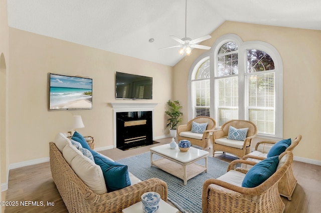 living room featuring arched walkways, lofted ceiling, a high end fireplace, wood finished floors, and baseboards