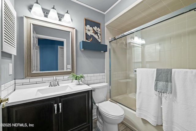 full bathroom featuring crown molding, tile walls, bath / shower combo with glass door, vanity, and toilet