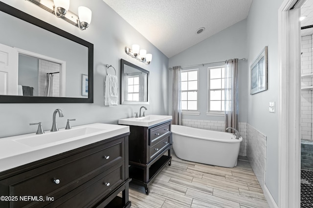 bathroom featuring lofted ceiling, separate shower and tub, tile walls, a textured ceiling, and vanity