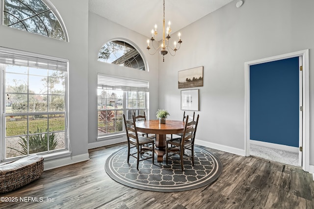 dining room with hardwood / wood-style flooring, high vaulted ceiling, and an inviting chandelier