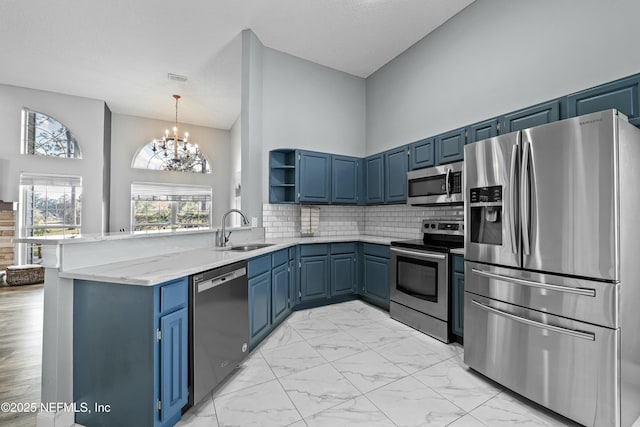 kitchen featuring sink, light stone counters, appliances with stainless steel finishes, a towering ceiling, and decorative backsplash