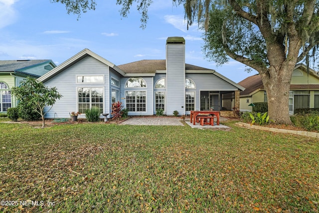 back of house with a sunroom, a patio area, and a lawn