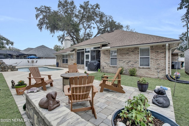 rear view of house featuring a fenced in pool, a patio, a sunroom, and a fire pit