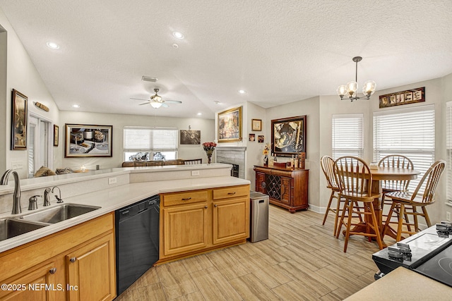 kitchen with pendant lighting, dishwasher, sink, light wood-type flooring, and a textured ceiling