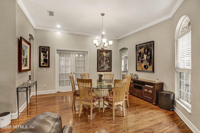 dining room with hardwood / wood-style flooring, ornamental molding, and a notable chandelier