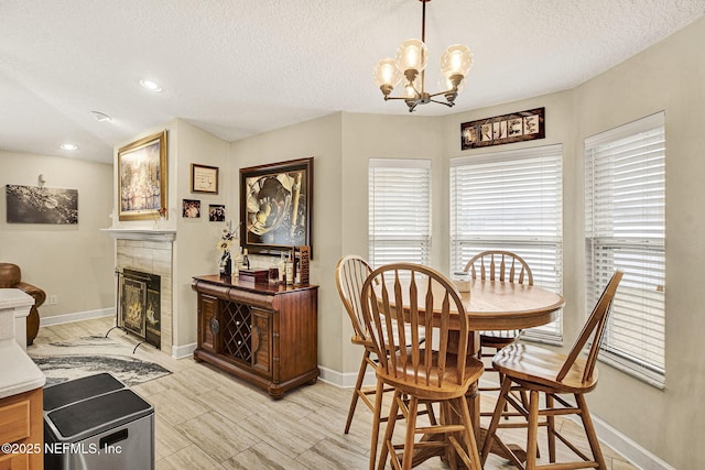 dining area featuring an inviting chandelier, a tile fireplace, and a textured ceiling