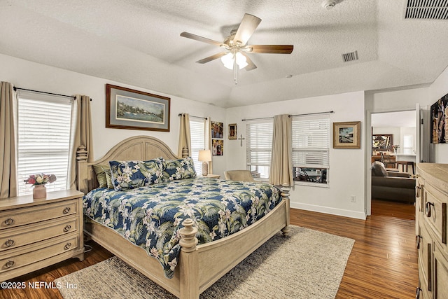 bedroom featuring a raised ceiling, vaulted ceiling, a textured ceiling, and dark hardwood / wood-style flooring