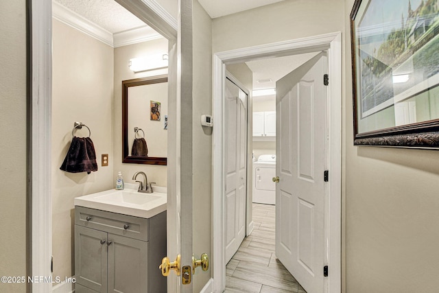 bathroom with vanity, washer / dryer, and ornamental molding