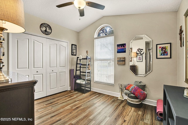 interior space with ceiling fan, vaulted ceiling, a textured ceiling, and light wood-type flooring