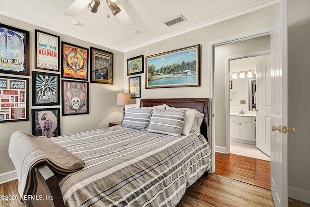 bedroom with sink, hardwood / wood-style flooring, ornamental molding, ceiling fan, and a textured ceiling