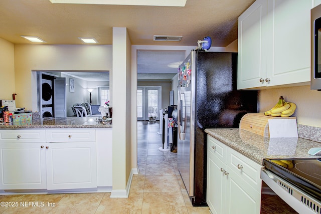 kitchen featuring stainless steel appliances, light stone countertops, light tile patterned floors, and white cabinets