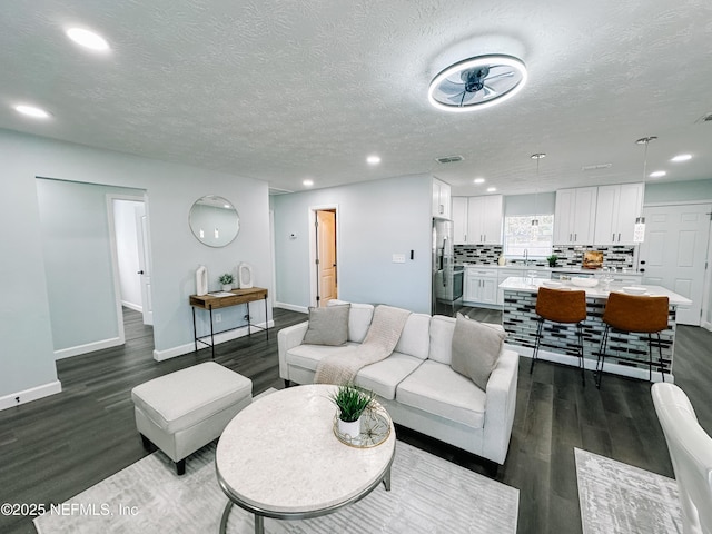 living room with dark wood-type flooring, sink, and a textured ceiling