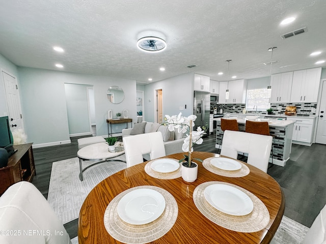 dining space with dark wood-type flooring, sink, and a textured ceiling