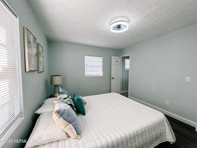 bedroom with a textured ceiling and dark hardwood / wood-style flooring