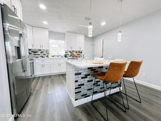 kitchen featuring pendant lighting, a breakfast bar, stainless steel appliances, a center island, and white cabinets