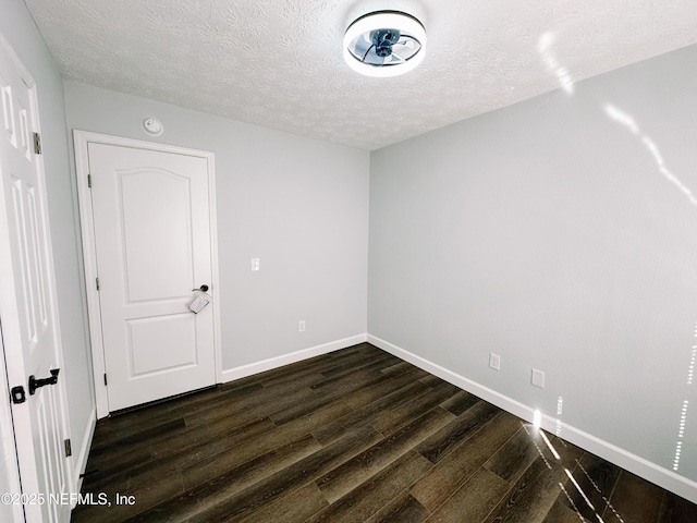 unfurnished room featuring dark wood-type flooring and a textured ceiling