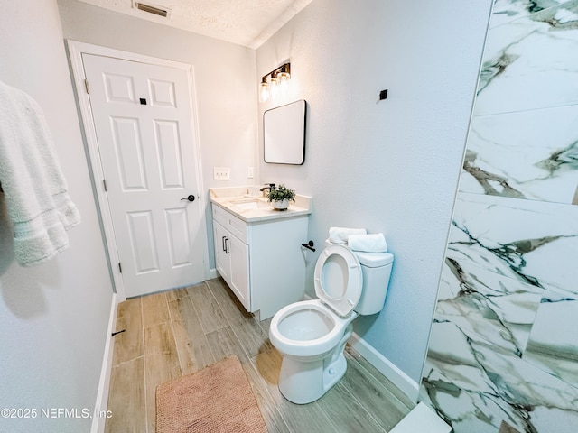 bathroom with vanity, a textured ceiling, and toilet