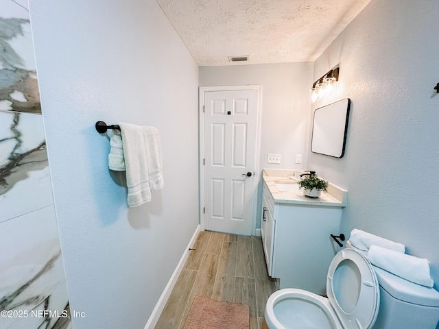 bathroom with vanity, hardwood / wood-style floors, toilet, and a textured ceiling