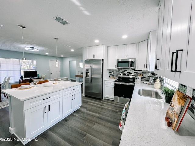 kitchen featuring white cabinetry, stainless steel appliances, sink, and hanging light fixtures