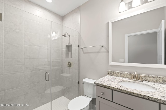 bathroom with vanity, a shower with shower door, and toilet