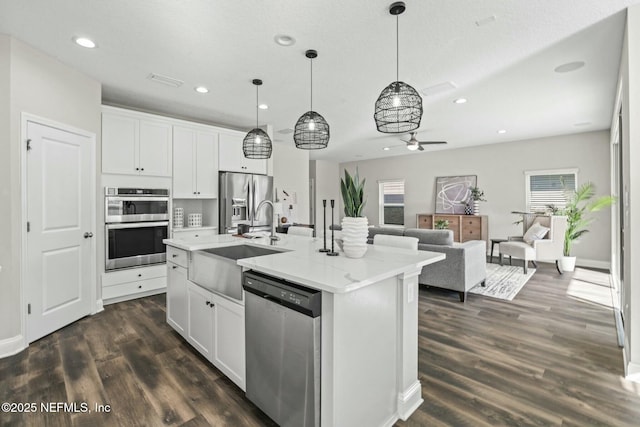 kitchen with an island with sink, appliances with stainless steel finishes, and white cabinets