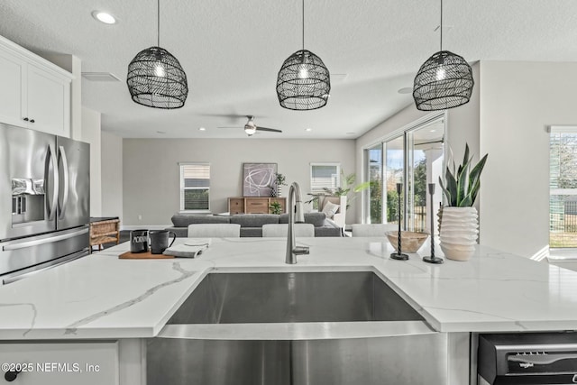 kitchen with pendant lighting, stainless steel fridge, and light stone countertops