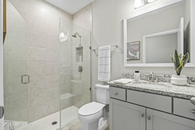 bathroom with a shower with door, vanity, and toilet