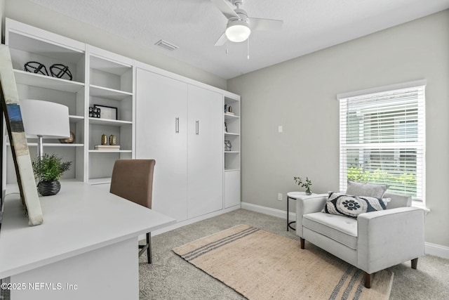 carpeted home office with a textured ceiling and ceiling fan