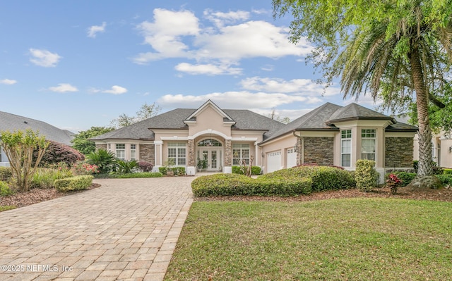 2095 Crown Dr, Saint Augustine, FL 32092 - view of front of house with stone siding, decorative driveway, an attached garage, a front yard, and french doors