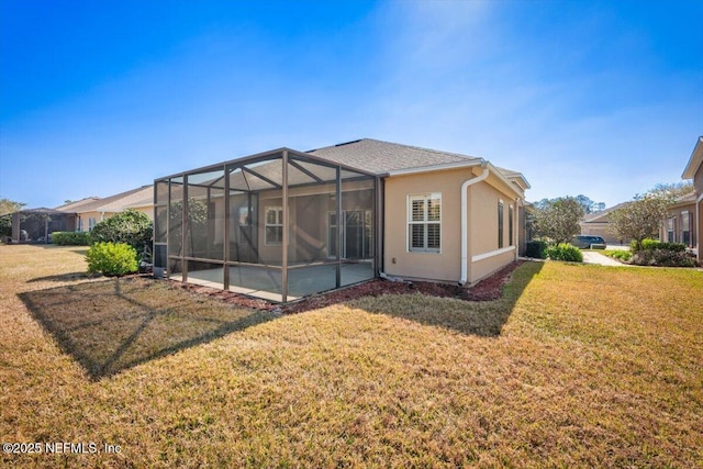 rear view of property featuring a patio, glass enclosure, and a lawn