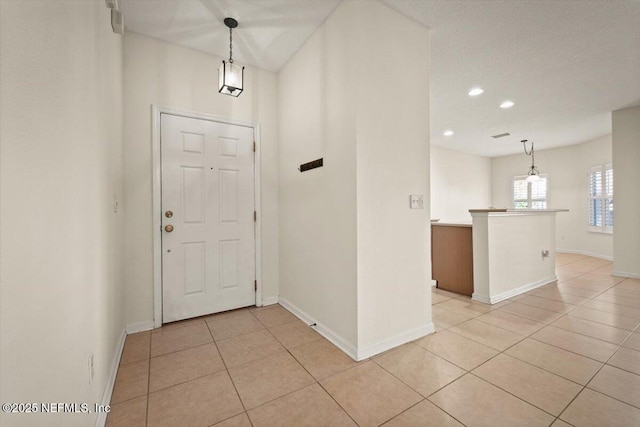 foyer entrance with a textured ceiling and light tile patterned floors