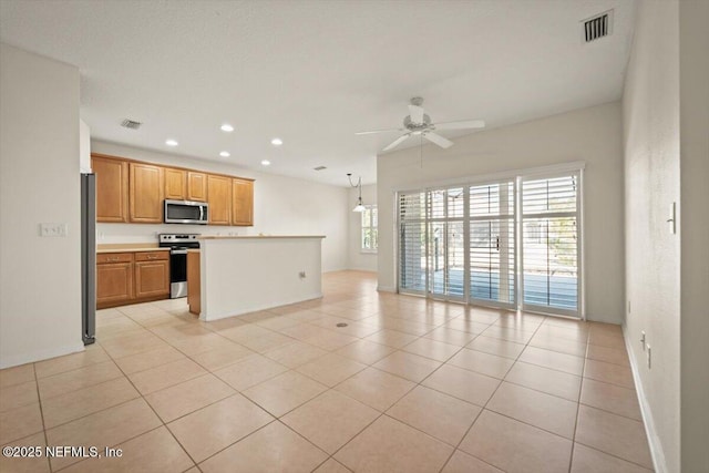 kitchen with light tile patterned flooring, ceiling fan, stainless steel appliances, and a kitchen island