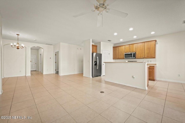 kitchen featuring pendant lighting, light tile patterned floors, stainless steel appliances, a kitchen island, and ceiling fan with notable chandelier