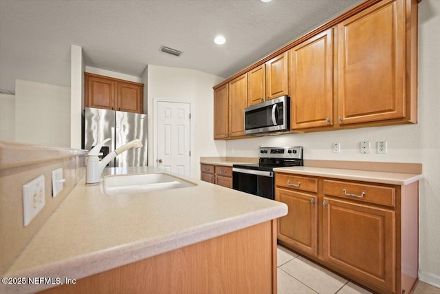 kitchen featuring stainless steel appliances, sink, a textured ceiling, and light tile patterned floors